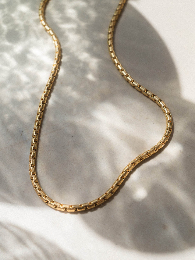 Goldene Kette mit klaren Linien auf hellem Hintergrund, PURELEI inspiriert.