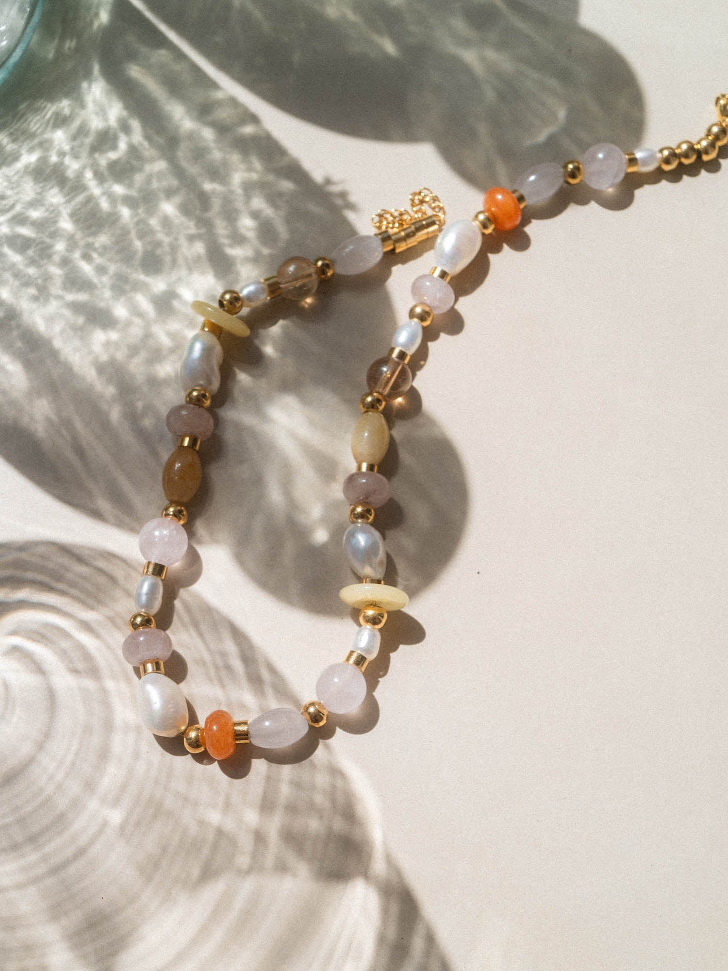 Goldene Perlenkette mit hellen Steinen, inspiriert von PURELEI, in sanfter Lichtstimmung.