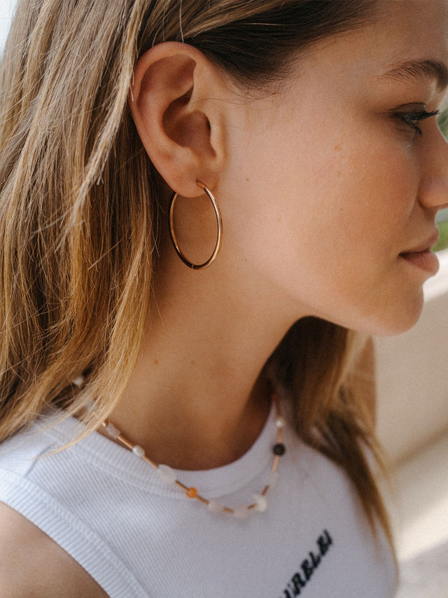 Goldene Creolen von PURELEI, elegant und zeitlos, getragen mit einem lässigen Outfit.