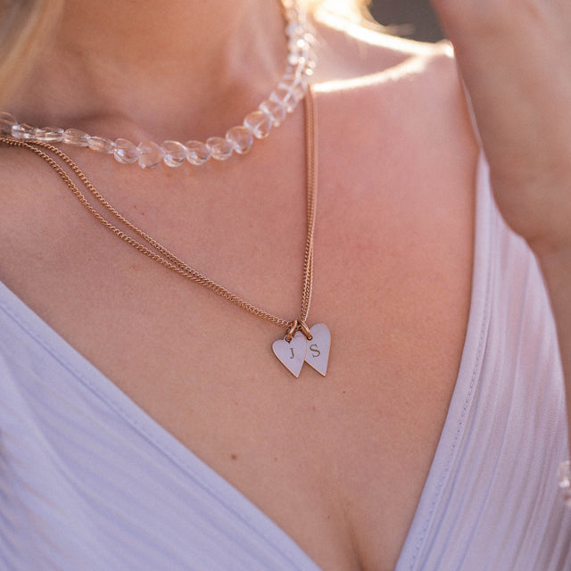 Zwei herzförmige Anhänger aus Silber und roségoldener Kette, getragen mit Aloha-Vibes von PURELEI.