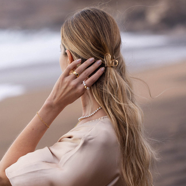 PURELEI Big Love Haarklammer aus goldener Zinklegierung im Herzdesign, elegant am welligen Haar getragen.