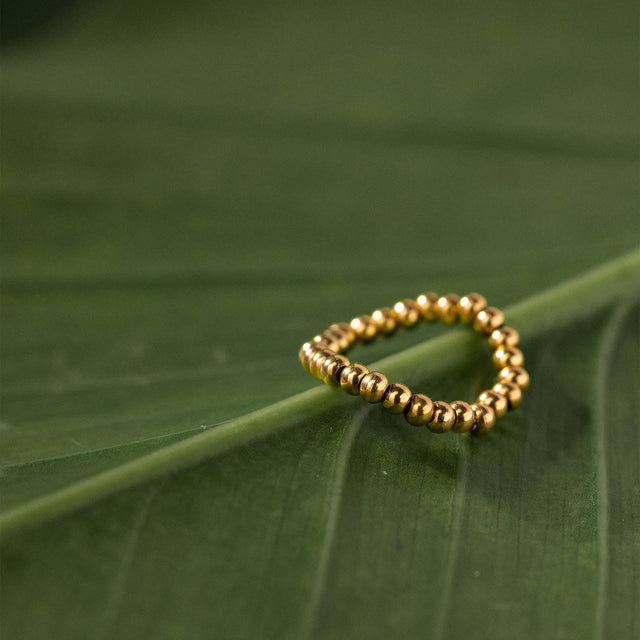 Goldener Ring mit Kugeldesign auf grünem Blatt, PURELEI inspiriert.