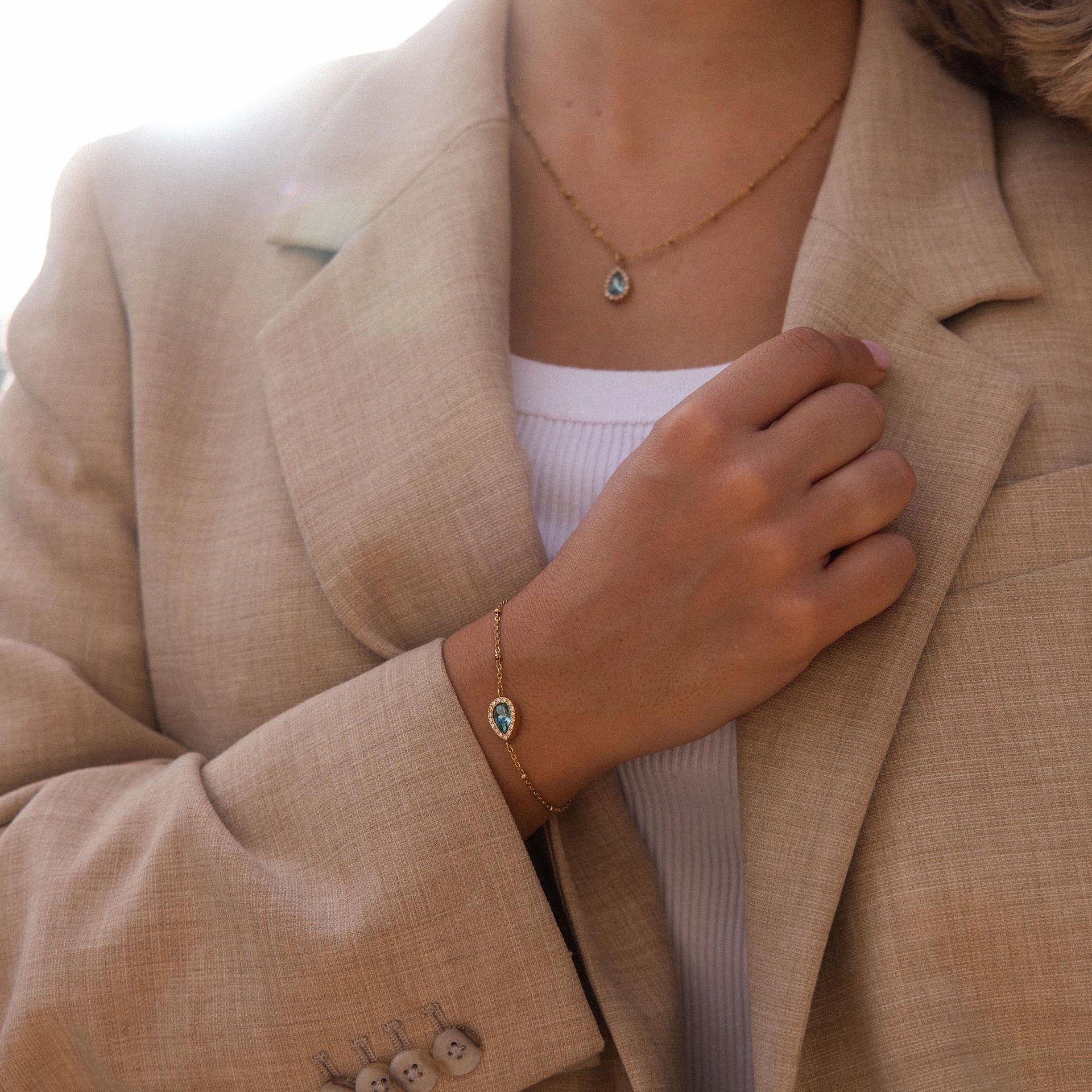PURELEI Bellezza Armband in Gold mit blauem Tropfenstein und kleinen Metallkugeln, elegant am Handgelenk getragen