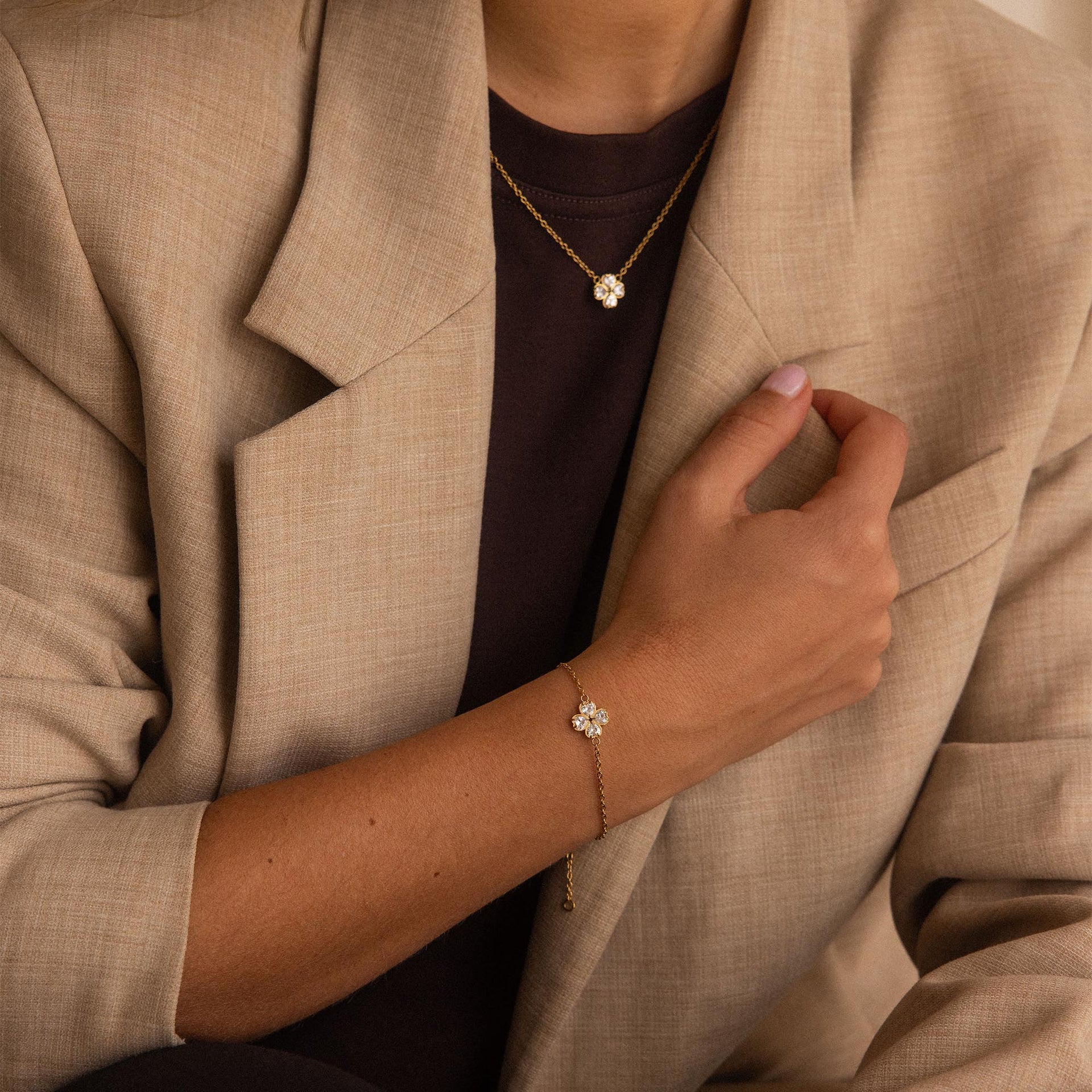 Goldene Kette und Armband mit Blütenmotiv, getragen in elegantem Outfit – PURELEI.