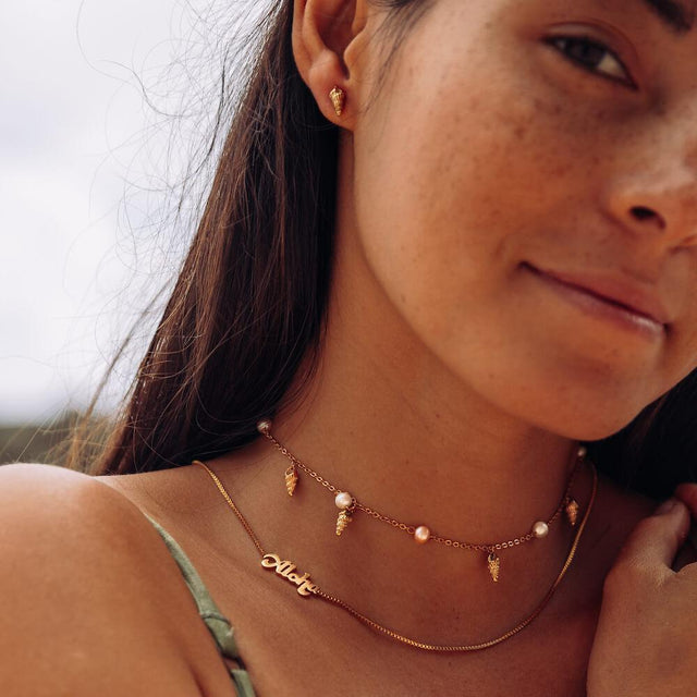 Akala Kette von PURELEI mit vergoldeten Muschel-Anhängern und Süßwasserperlen, femininer Island-Spirit am Hals.