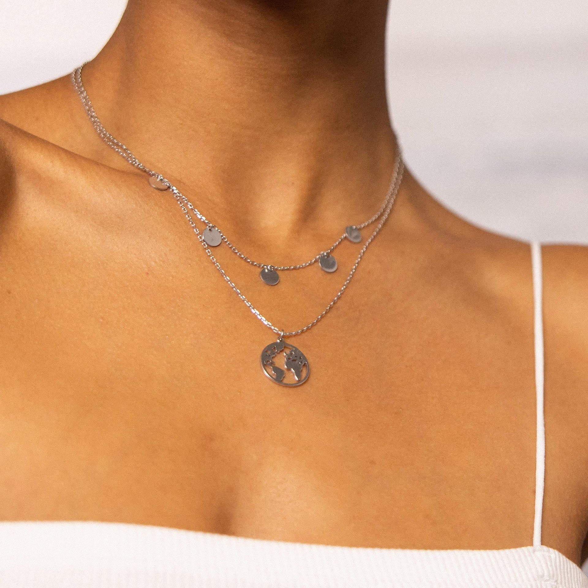 Silberne Kette mit Anhänger und kleinen Kreisen, getragen auf nackter Haut, PURELEI.