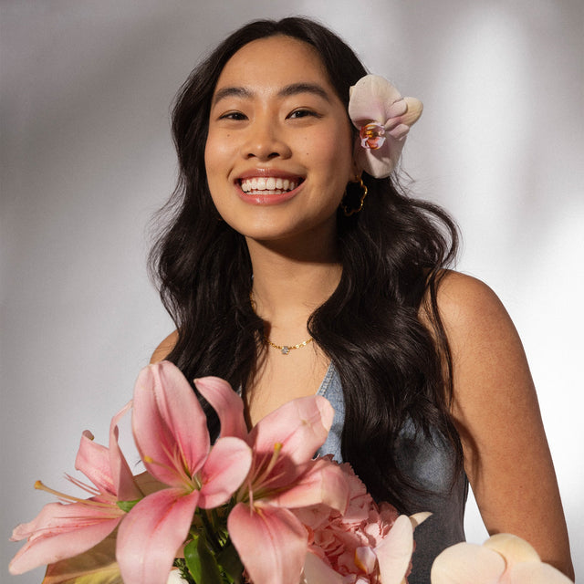 PURELEI Bloom Ohrringe in goldener Blütenform, elegant getragen, strahlen feminine Leichtigkeit und Insel-Spirit aus.