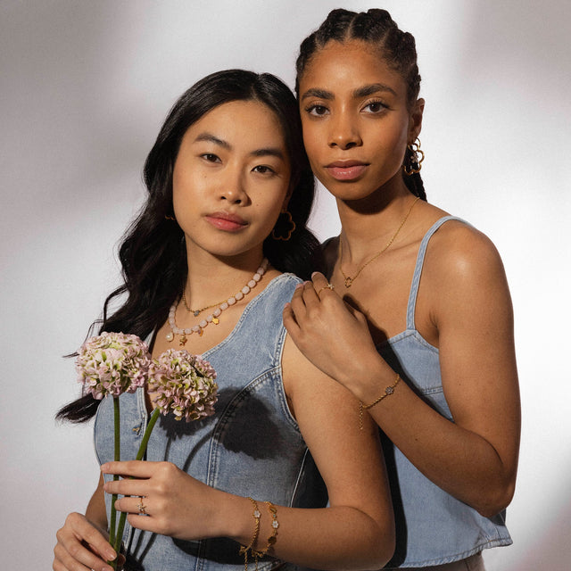 Zarte PURELEI Schmuckstücke, Perlenkette und goldene Creolen, in warmem Licht, feminin und elegant.