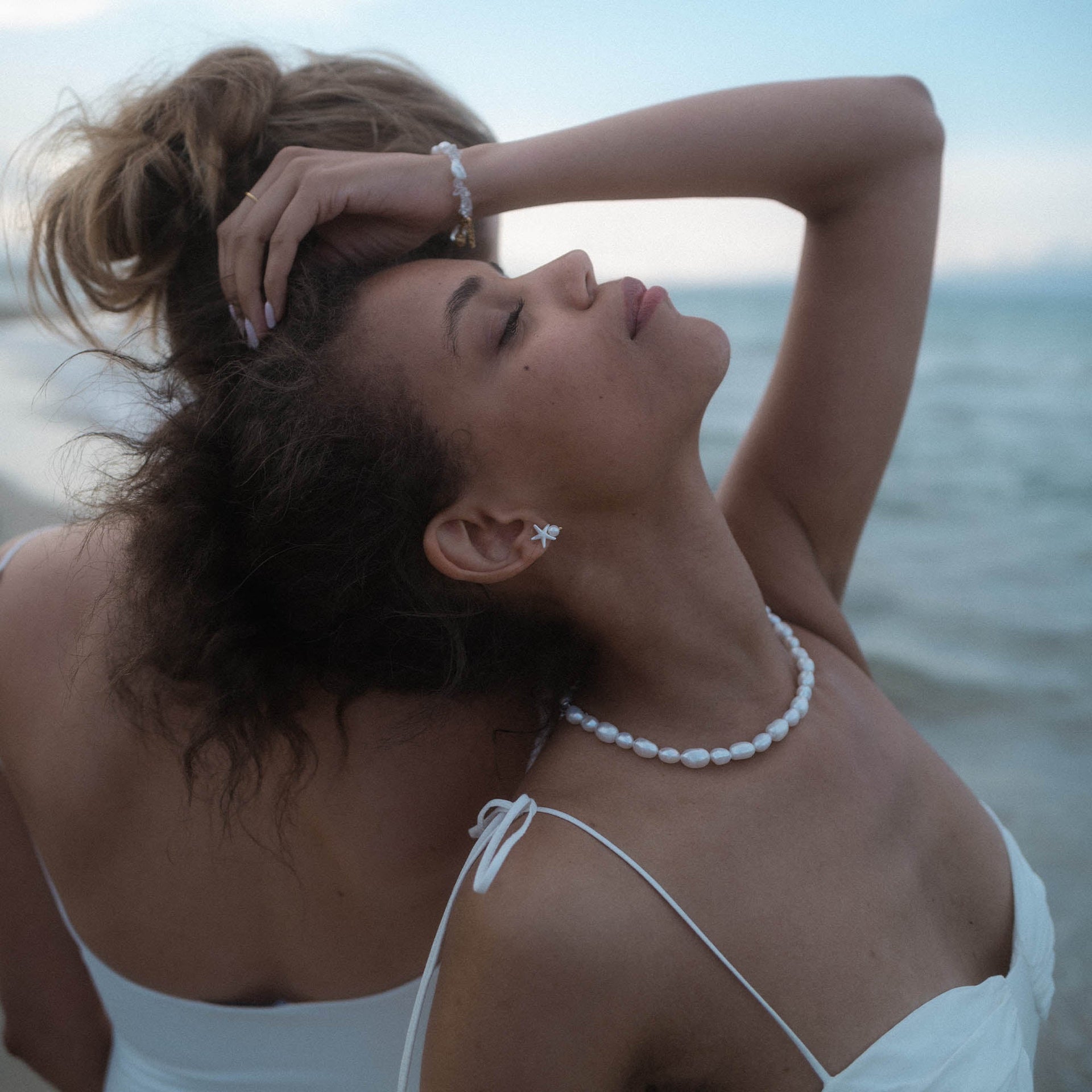 Perlenkette und Ohrstecker von PURELEI, elegant und feminin, am Strand getragen.