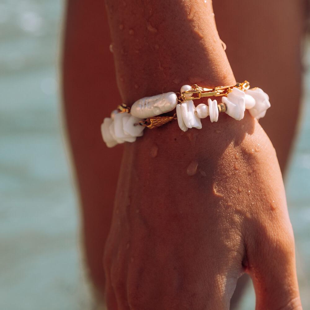PURELEI Wela Armband mit Muschel und Perlen, goldfarben, wasserfest am Handgelenk im sonnigen Strandlicht
