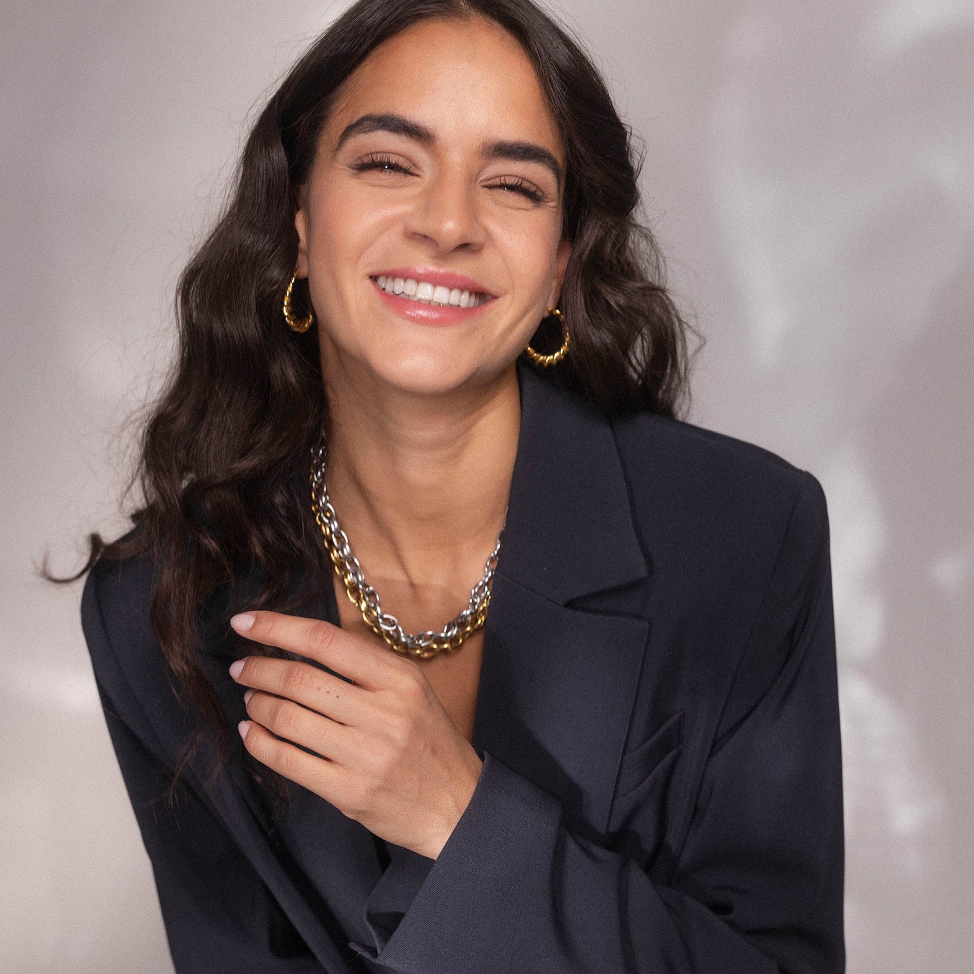 Kette aus silbernem Metall und Creolen, getragen mit einem eleganten Blazer – PURELEI Stil.