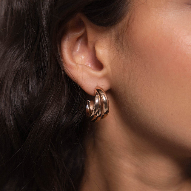 Roségoldene Creolen mit geschwungenem Design, getragen am Ohr, von PURELEI.