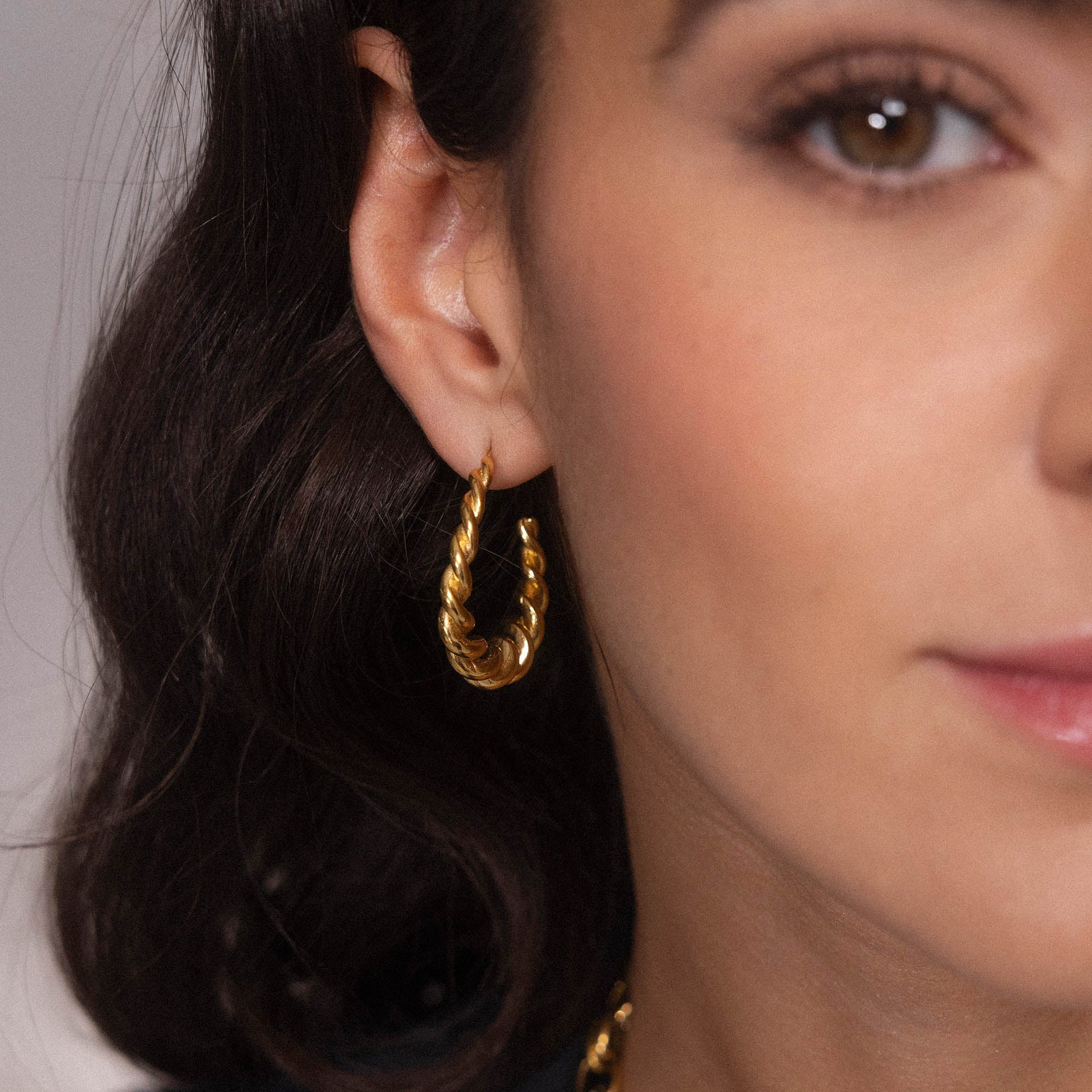 Roségoldene Creolen mit gedrehter Struktur, getragen am Ohr, von PURELEI.