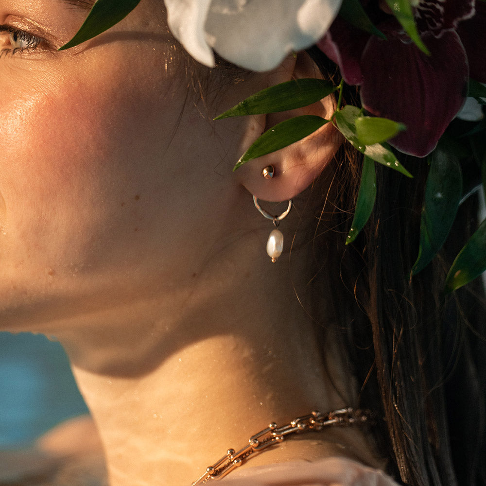 Elua Ohrringe in Silber mit schimmernder Keshi-Perle, getragen am Ohr in warmem Sonnenlicht von PURELEI