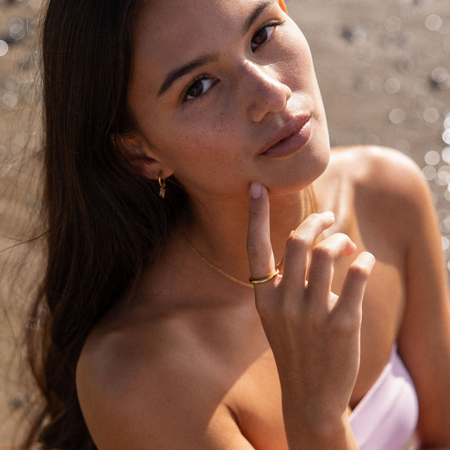 PURELEI Shine Bright Ohrringe aus 18K Gold mit weißen Zirkonia, elegant und zeitlos am Strand getragen.