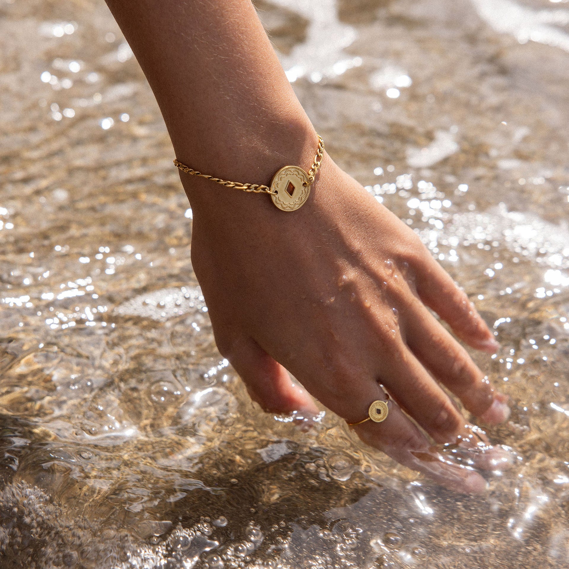 Lolani Armband von PURELEI in Gold mit hawaiianischem Coin, wasserfest, zart am Handgelenk im Meeresspiel.