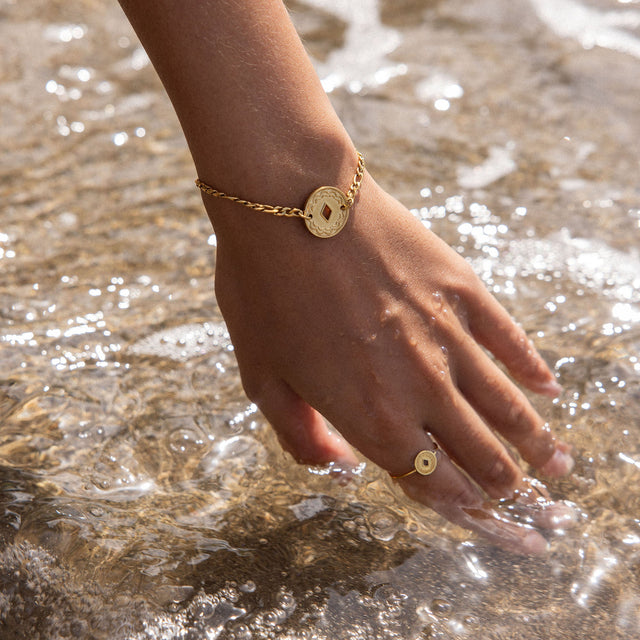 Lolani Armband von PURELEI in Gold mit hawaiianischem Coin, wasserfest, zart am Handgelenk im Meeresspiel.