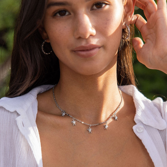 Silberne Kette mit Schildkröten-Anhängern, getragen von einer Frau im Freien – PURELEI.