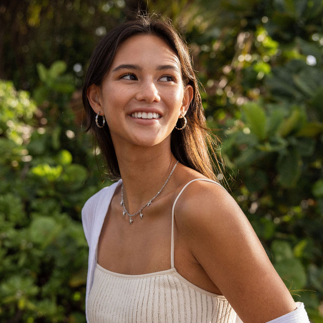 Nickelfreie Creolen und zarte Kette von PURELEI, umgeben von tropischer Natur.