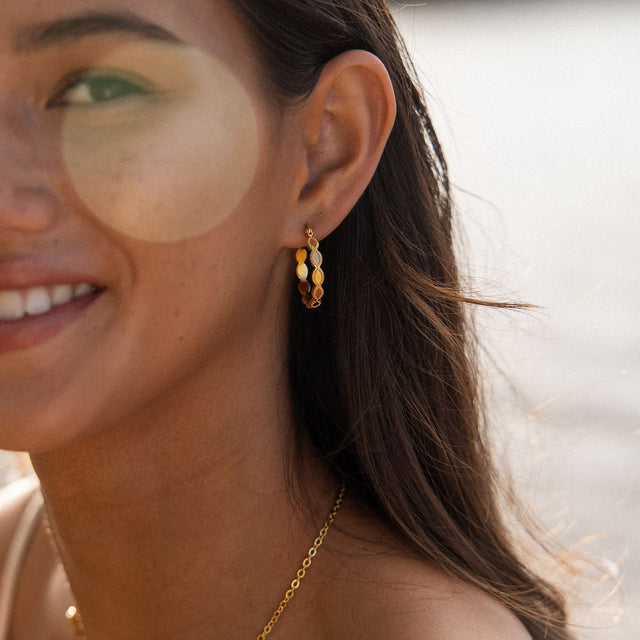 Roségoldene Creolen mit Muschel-Details, getragen von einer lächelnden Frau, PURELEI.