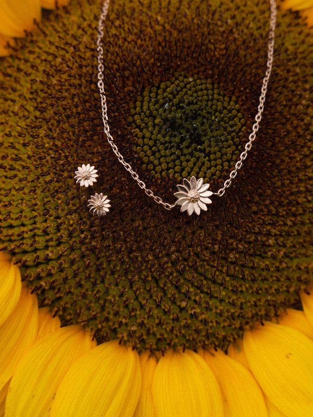 Silberne Blütenkette und Ohrringe auf Sonnenblumen-Hintergrund von PURELEI.
