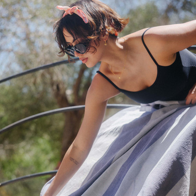 Frau in schwarzem Top und grauem Rock, inspiriert von PURELEI, mit Sonnenbrille im Freien.