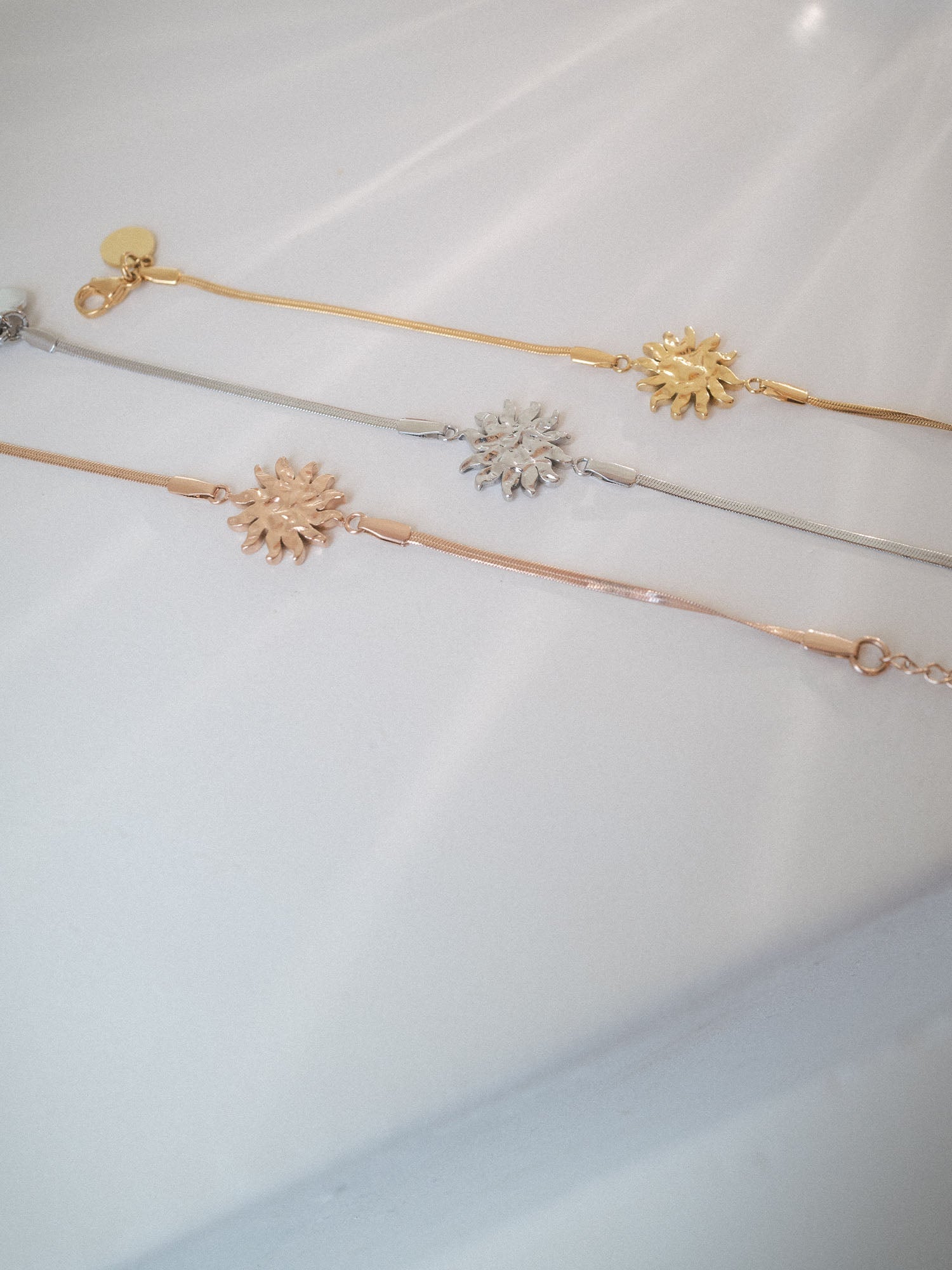 Iconic Sun Armband in Gold, Silber und Roségold mit filigranem Snake-Chain-Design von PURELEI auf hellem Hintergrund.