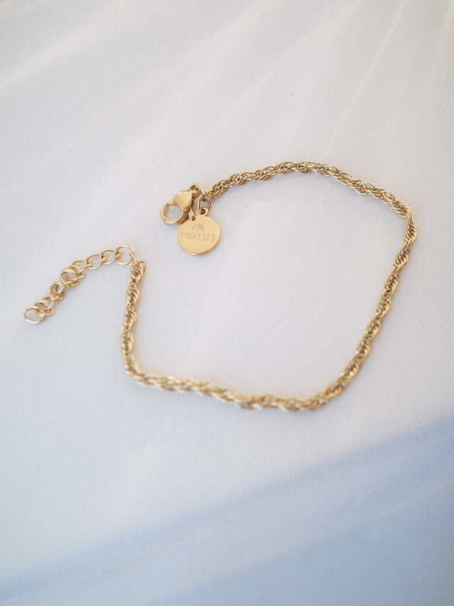 Goldene Kette mit geflochtenem Design und PURELEI-Anhänger auf hellem Hintergrund.