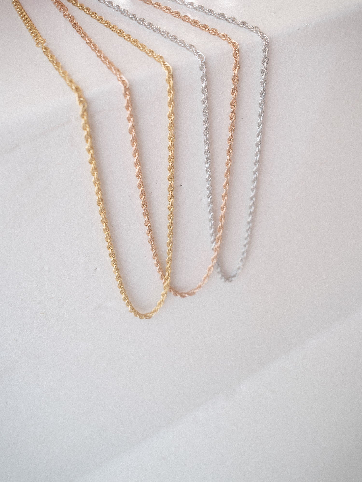 Zarte Ketten in Gold und Silber, elegant auf hellem Untergrund drapiert – PURELEI.