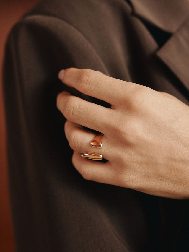 Roségoldener Ring mit geschwungenem Design, getragen an einer Hand, inspiriert von PURELEI.