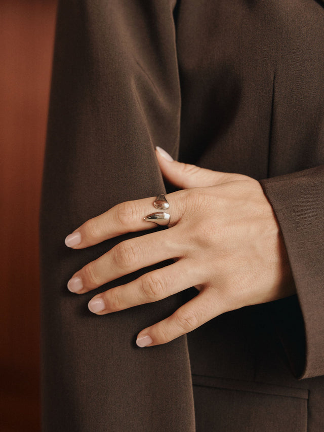 Eleganter Ring aus Roségold mit geschwungenem Design, getragen an einer Hand, inspiriert von PURELEI.