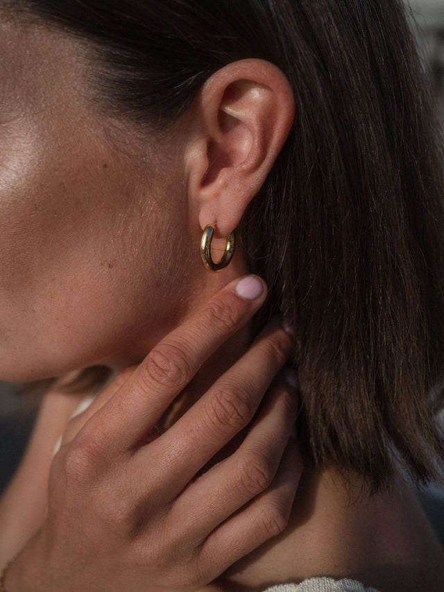 Kleine goldene Small Glamorous Ohrringe von PURELEI, edel und zeitlos, in warmer Lichtstimmung am Ohr getragen.