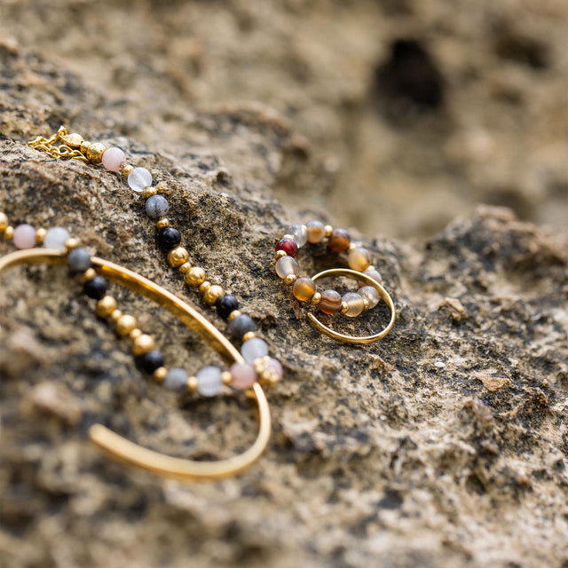 PURELEI Anxiety Mahina Club Mokupuni Ring mit Naturstein- und Edelstahlperlen auf rauem Strandgestein