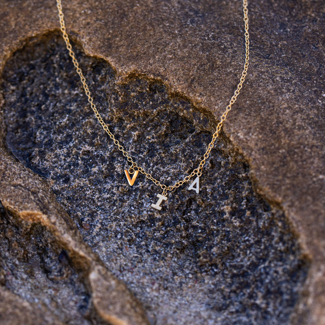 Feine Via Kette aus vergoldetem Edelstahl mit Buchstabenanhängern auf natürlichem Stein – elegant und zeitlos von PURELEI.