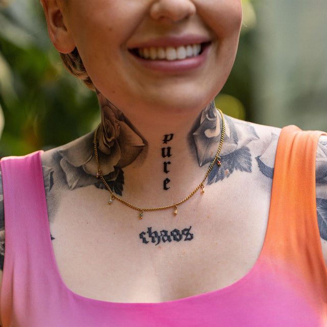 Zarte, roségoldene Kette mit Anhängern, getragen von einer tätowierten Frau, PURELEI inspiriert.