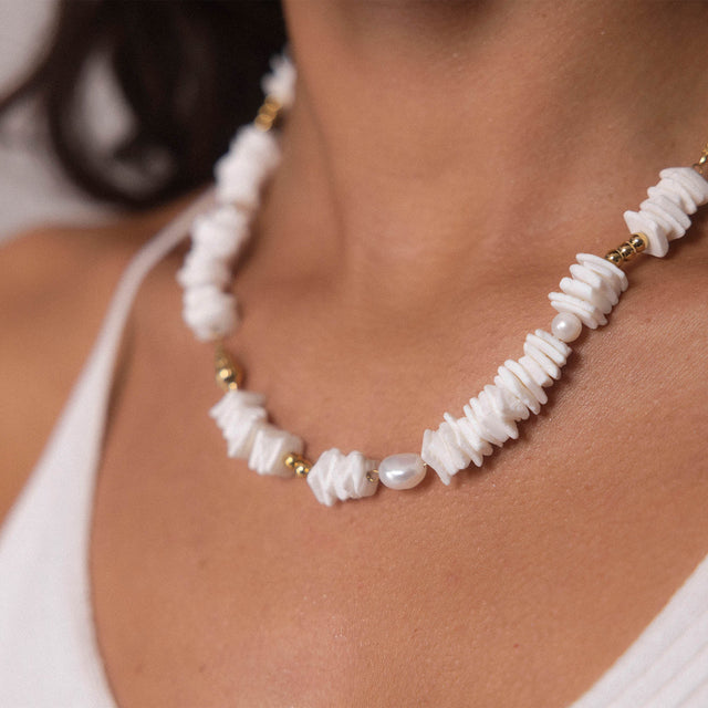 PURELEI Wela Kette mit weißen Muschelstücken und Perlen in Gold an warmem Hautton, elegant und feminin.
