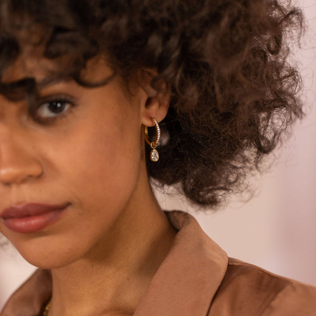 Roségoldene Creolen mit funkelndem Anhänger, getragen von einer Frau, PURELEI.