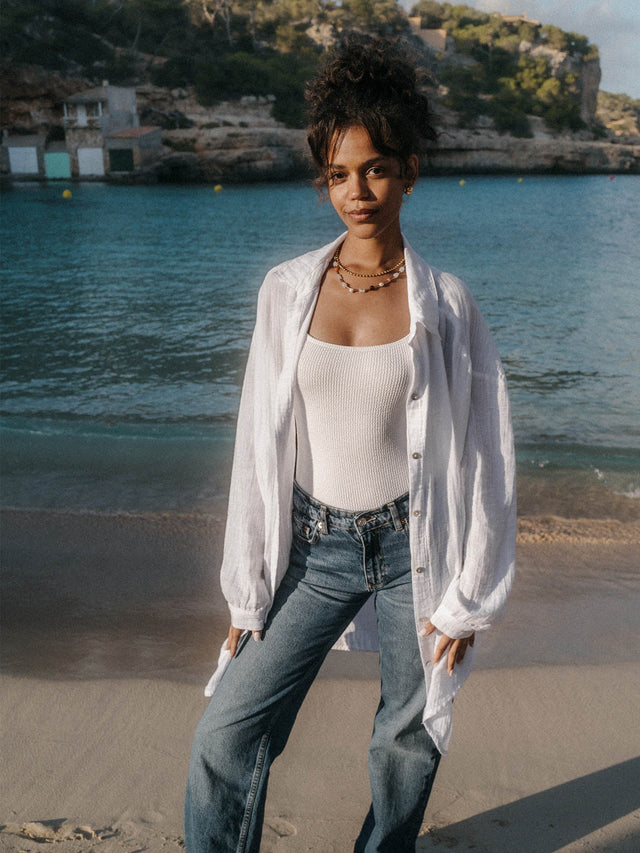 Weiße, leichte Breeze Bluse aus Baumwolle mit PURELEI Stickerei, lässig am Strand getragen, pure Leichtigkeit.