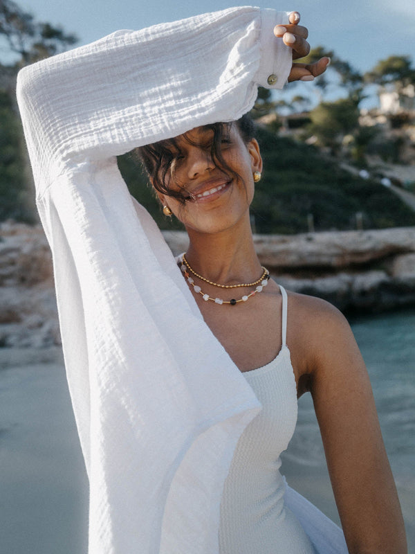 Weißes, luftiges Kleid mit PURELEI Schmuck, strahlende Stimmung am Strand.
