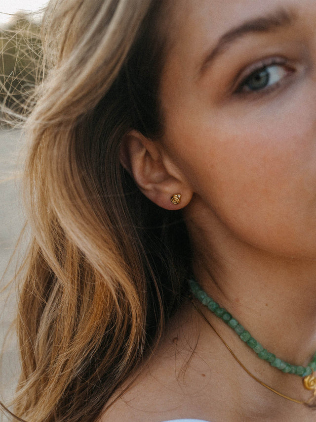 Goldene Ohrstecker mit spiralförmigem Design, getragen von einer Frau, PURELEI.