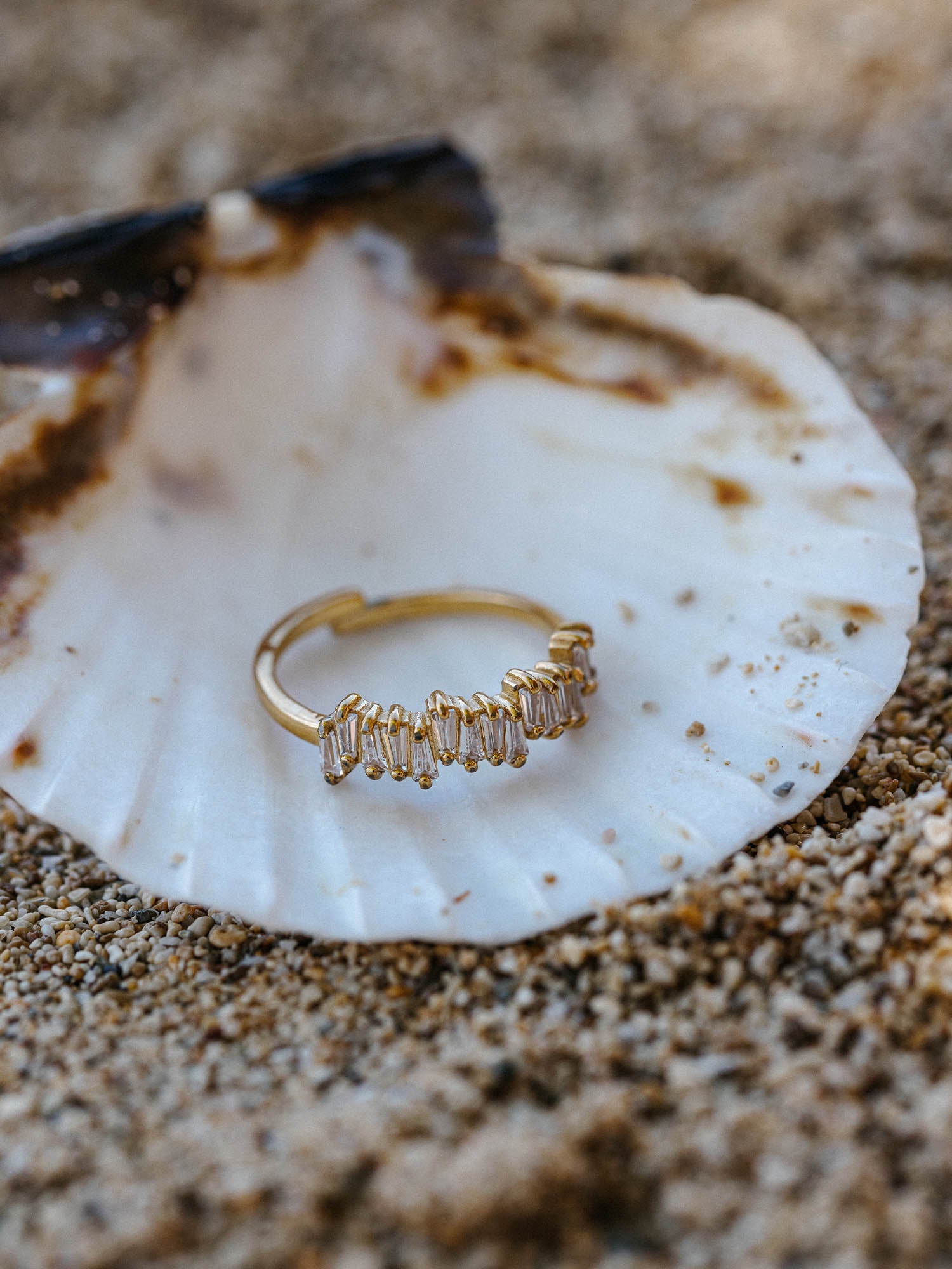 Goldring mit facettiertem Design auf Muschel, PURELEI, am Strand inszeniert.