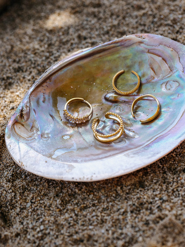 Silberne Ringe in verschiedenen Designs auf einer Muschel, inspiriert von PURELEI.