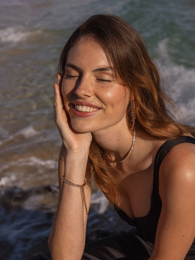 Elegante PURELEI Kette und Armband aus Gold, strahlend am Strand, inspiriert von Aloha-Vibes.