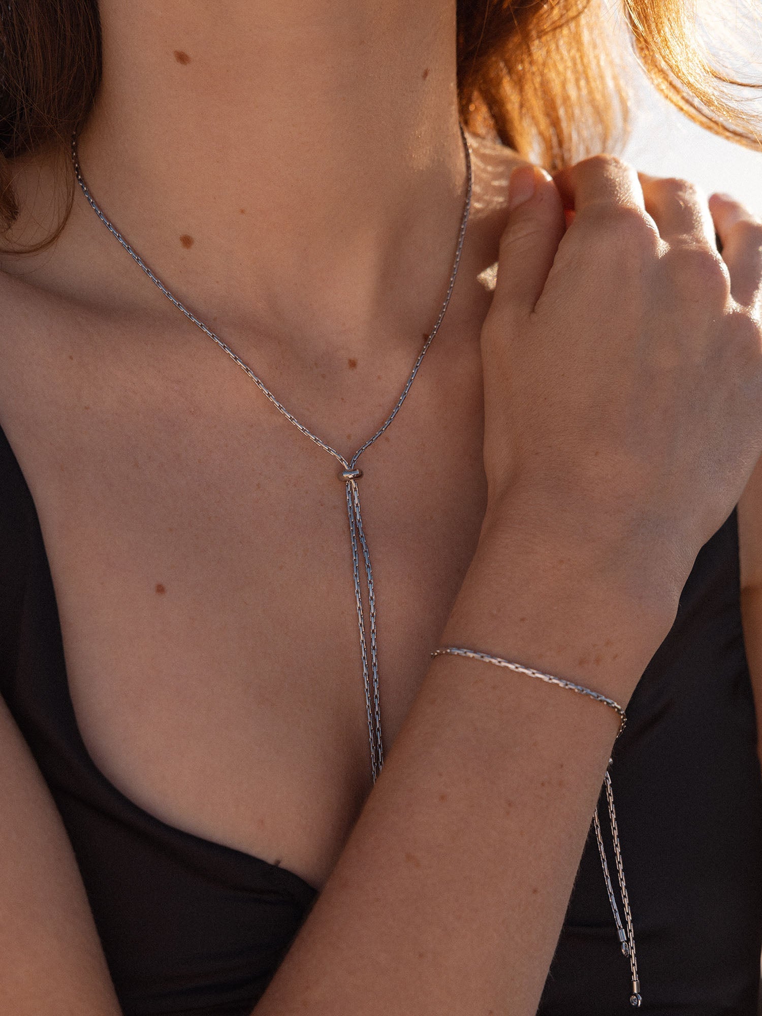 Silberne Kette und Armband von PURELEI, elegant und minimalistisch, in warmem Licht getragen.