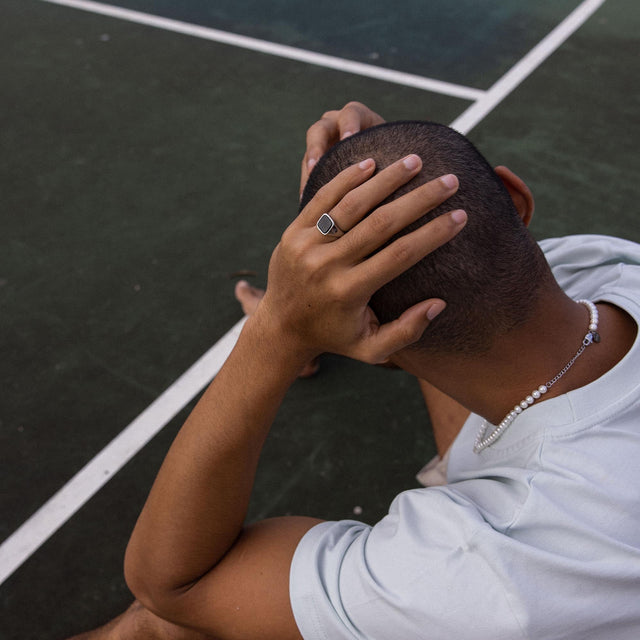 Schwarzer Ring aus Silber mit quadratischem Stein, getragen von PURELEI, in entspannter Stimmung.