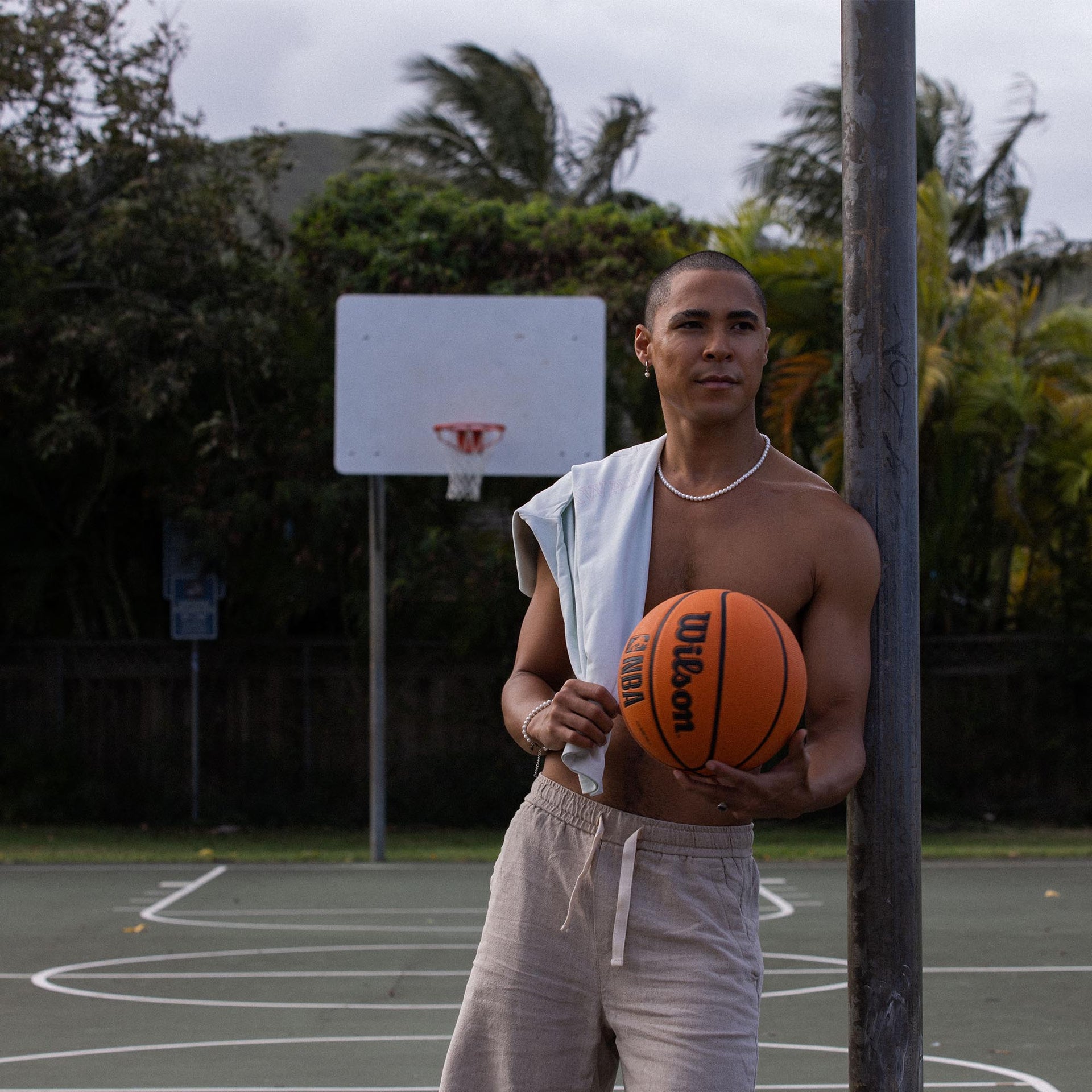 Mann mit Basketball und PURELEI Perlenkette, sportlich und entspannt auf dem Platz.