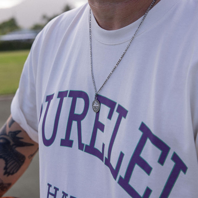 Silberne Kette mit Kompass-Anhänger, getragen über PURELEI T-Shirt, lässige Strandstimmung.