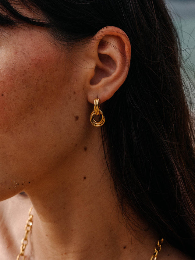 PURELEI He Nui Ohrringe aus vergoldetem Edelstahl, ineinander verschlungene Ringe, elegant am Ohr getragen.