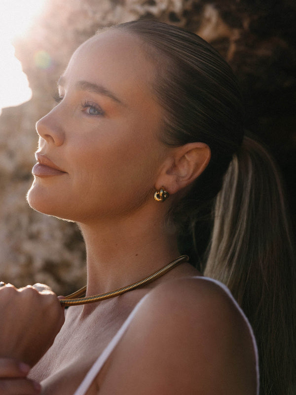 Elegante PURELEI Kette und Creolen, goldfarben, in warmem Licht, feminine Ausstrahlung.