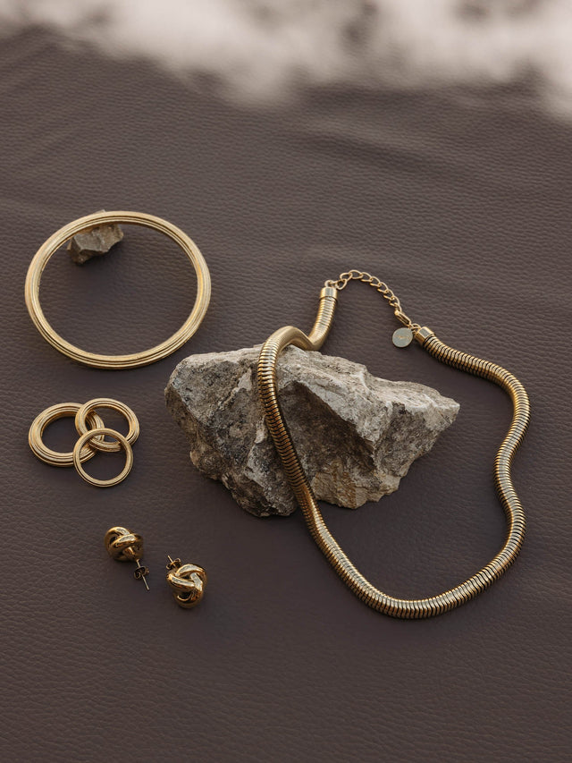 Silberne Schmuckstücke von PURELEI: Kette, Ringe und Ohrringe auf dunklem Hintergrund.